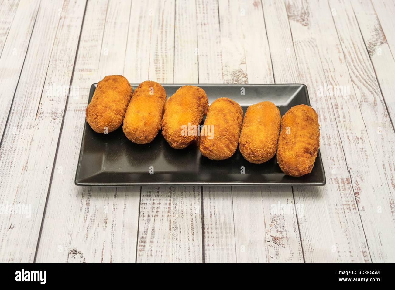 Süße Kroketten, gefüllt mit Schokolade oder Pudding, paniert und frittiert, mit Puderzucker bestäubt und als ungewöhnliches Dessert serviert Stockfoto