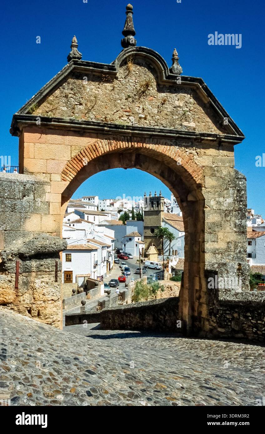 Historisches Farbfoto des Eingangs zur Puente Nuevo, Steinbogenbrücke und Wahrzeichen von Ronda, Kleinstadt in Spanien, Andalusien, bei schönem Somm Stockfoto