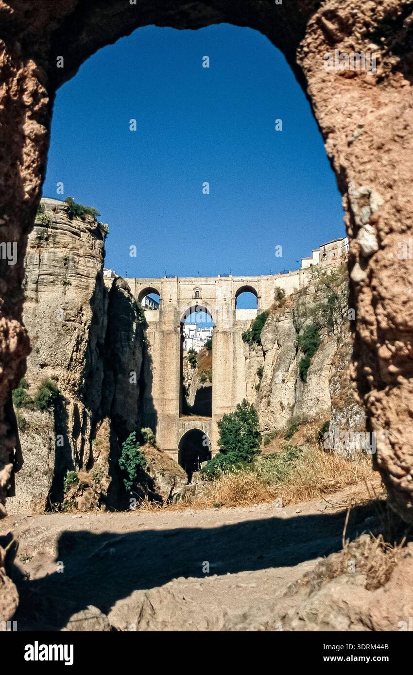 Historisches Farbfoto der Puente Nuevo, Steinbogenbrücke und Wahrzeichen von Ronda, Kleinstadt in Spanien, Andalusien, mit steilen Felsen bei schöne Stockfoto