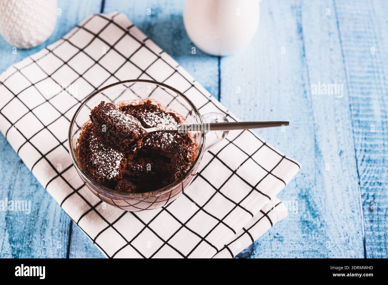 Hausgemachter süßer Kuchen in einem Becher, der in der Mikrowelle auf dem Tisch gemacht wurde Stockfoto