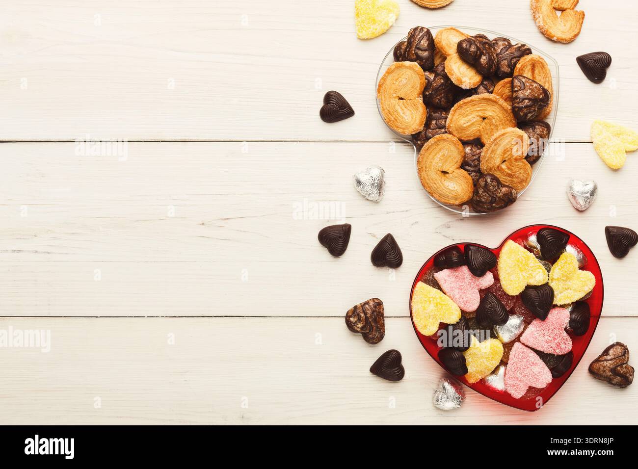 Sammlung herzförmiger Bonbons und Kekse auf einem Holztisch Stockfoto