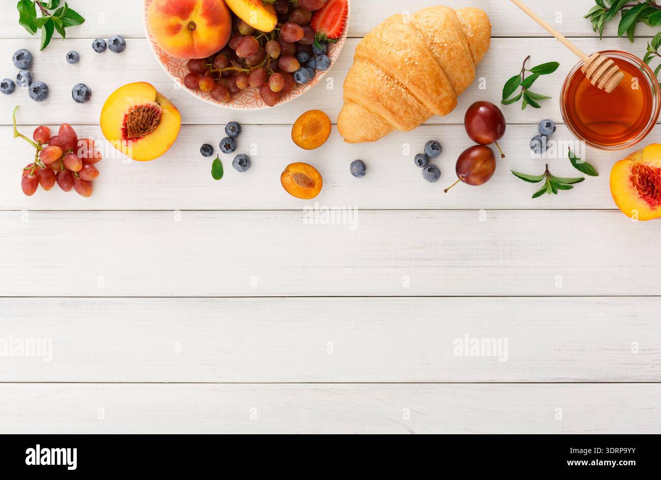 Frisches Obst und Gebäck auf einem Holztisch mit Honig auf der Seite Stockfoto