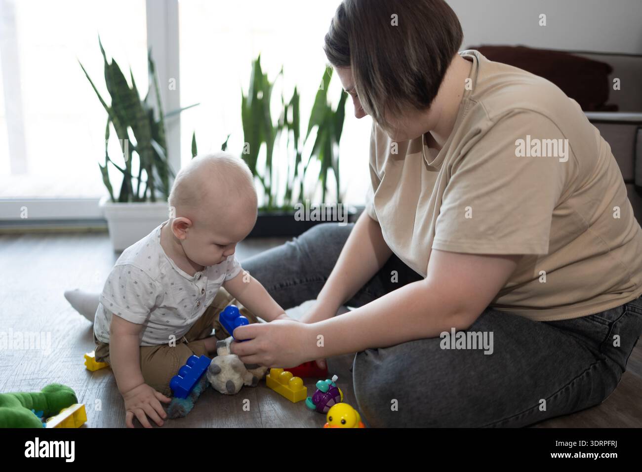 Mutter Bringt Dem Baby Bei, Blöcke Zu Stapeln Und Formen Zu Erforschen, Warme Mothers Day-Szene Mit Patientenführung, Feinmotorik Und Enge Interaktion Mit Dem Mutterkind In Der Häuslichen Umgebung. Stockfoto