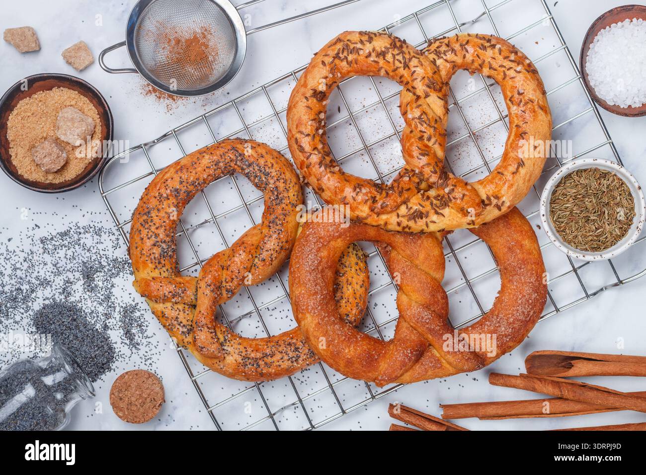 Brezel. Frisch gebackene Brezeln mit Zucker, Mohn, Zimt und Kümmel. Köstliches hausgemachtes süßes und salziges Gebäck und Essen Stockfoto