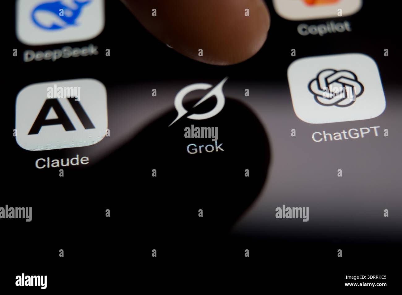 Auf einem Smartphone-Bildschirm werden die Anwendungssymbole DeepSeek, Grok, Claude und ChatGPT angezeigt, die einen Finger zeigen, der dabei ist, einen KI-Chatbot aus einer Div auszuwählen Stockfoto