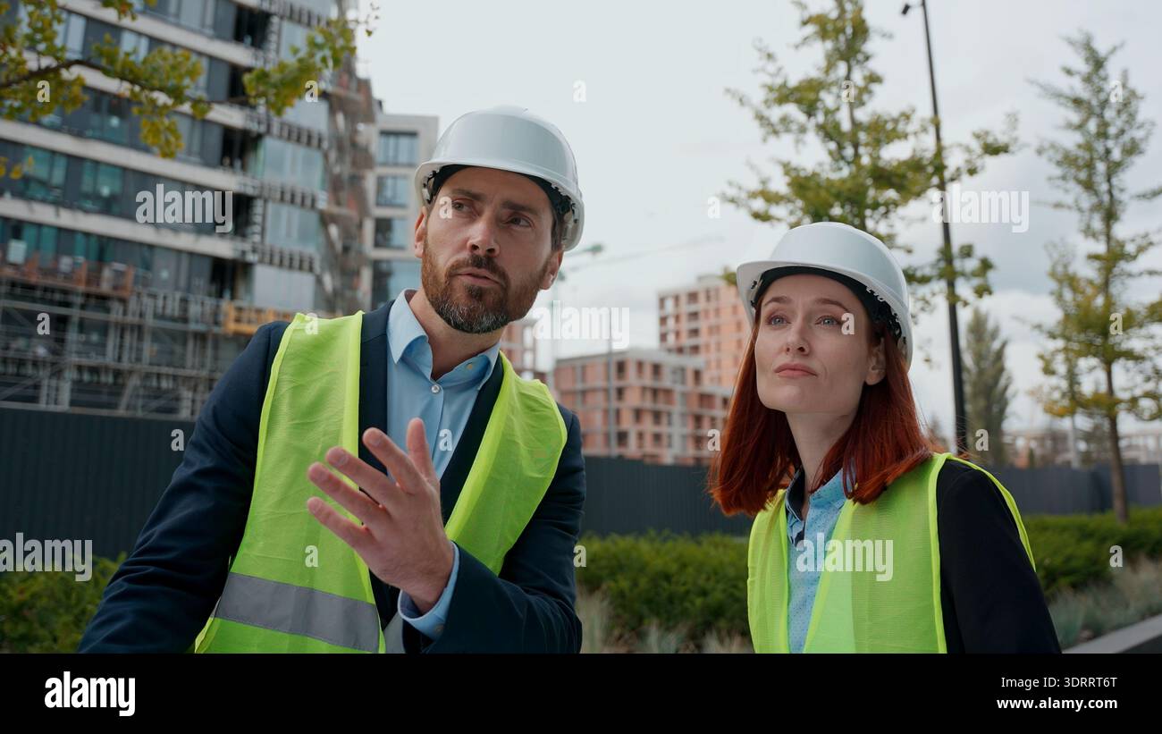 Bauunternehmer zwei Ingenieure Mann Frau im Gespräch Blick auf Bauplan Vielfalt Menschen Kollegen Bauarbeiter Architekten tragen Sicherheitsuniform Stockfoto