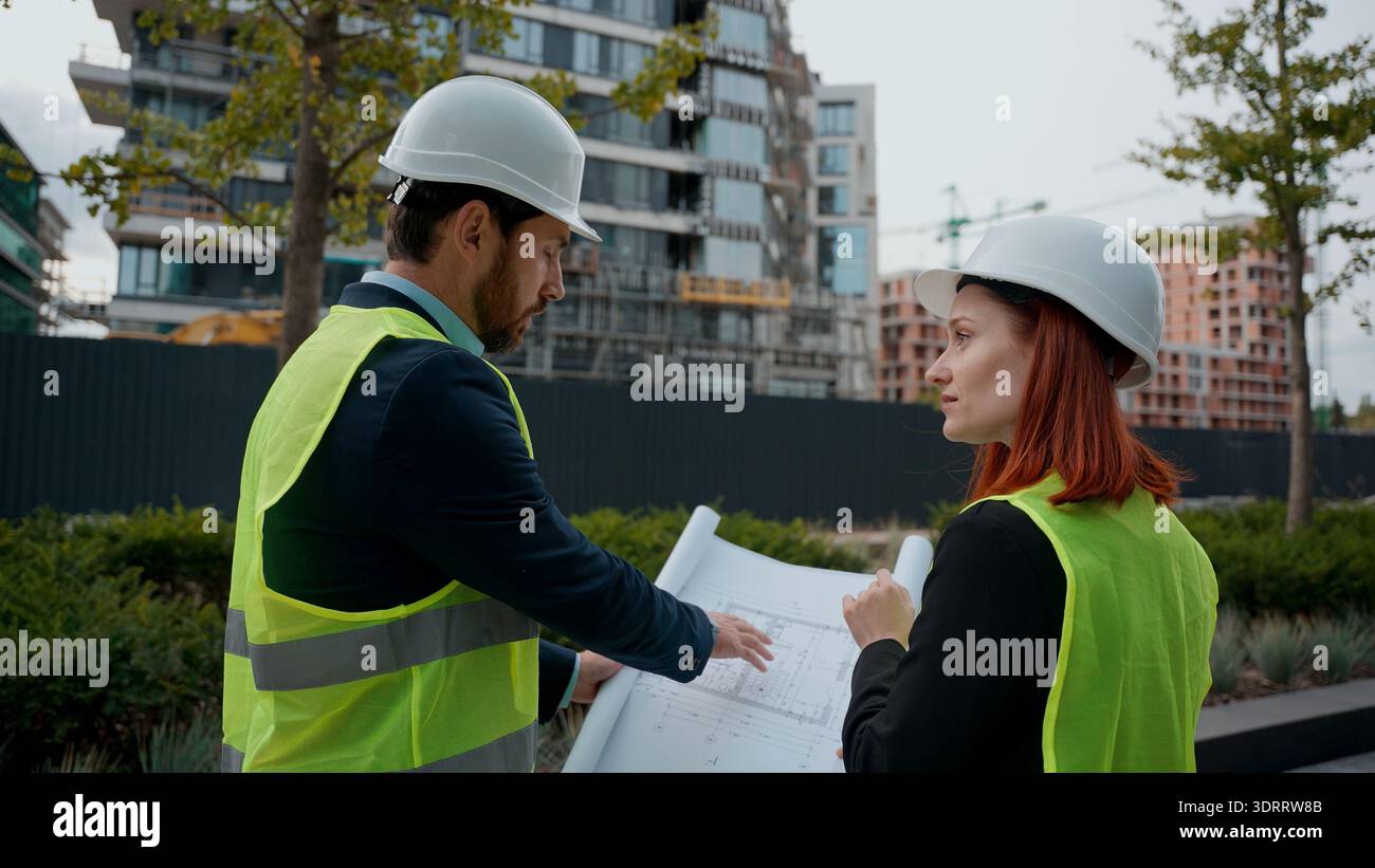 Zwei Bauingenieure, die Baupläne prüfen, diskutieren über Gebäude Projekt Teamwork Frau Mann zeigt Stadtmanager, die Zusammenarbeit planen Stockfoto