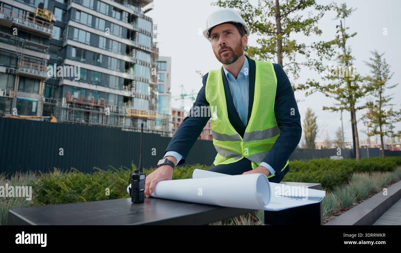 Nachdenklicher männlicher Architekt nachdenklich umschauen Bauplan prüfen Stadtinfrastruktur Herstellung denken Arbeiter Reparaturarbeiter Mann in denken Stockfoto
