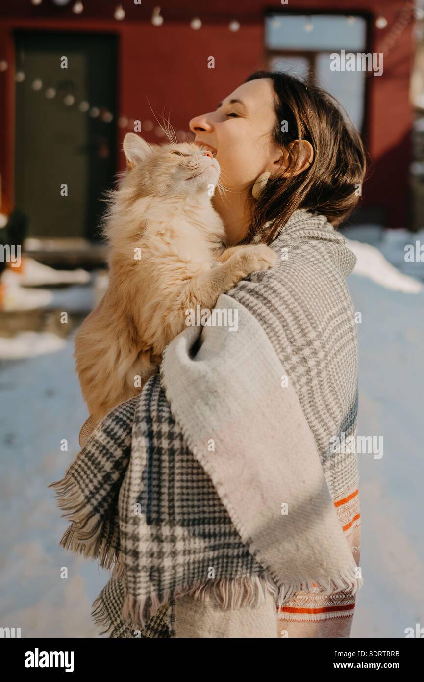 Fröhliche Tierumarmung. Helles Sonnenlicht Fängt Frau, Die Bond Mit Ihrem Feline Companion Versiegelt Stockfoto