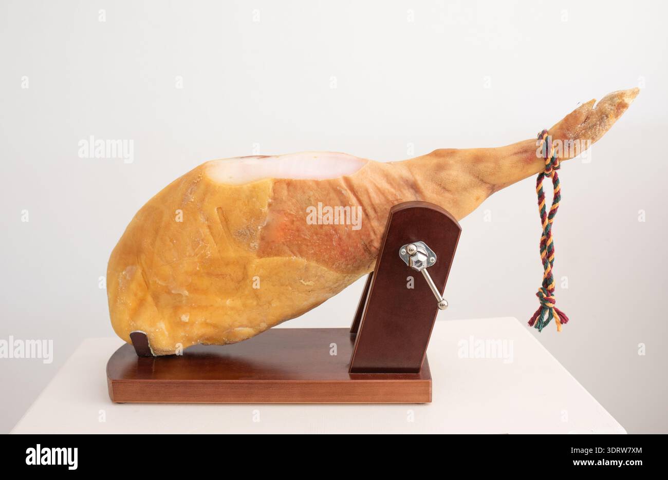 Traditioneller spanischer trocken gepökelter Schinken, der auf einem speziellen Halter fixiert ist und für das professionelle Schneiden von Cortador in hellen Studioräumen geeignet ist. Stockfoto