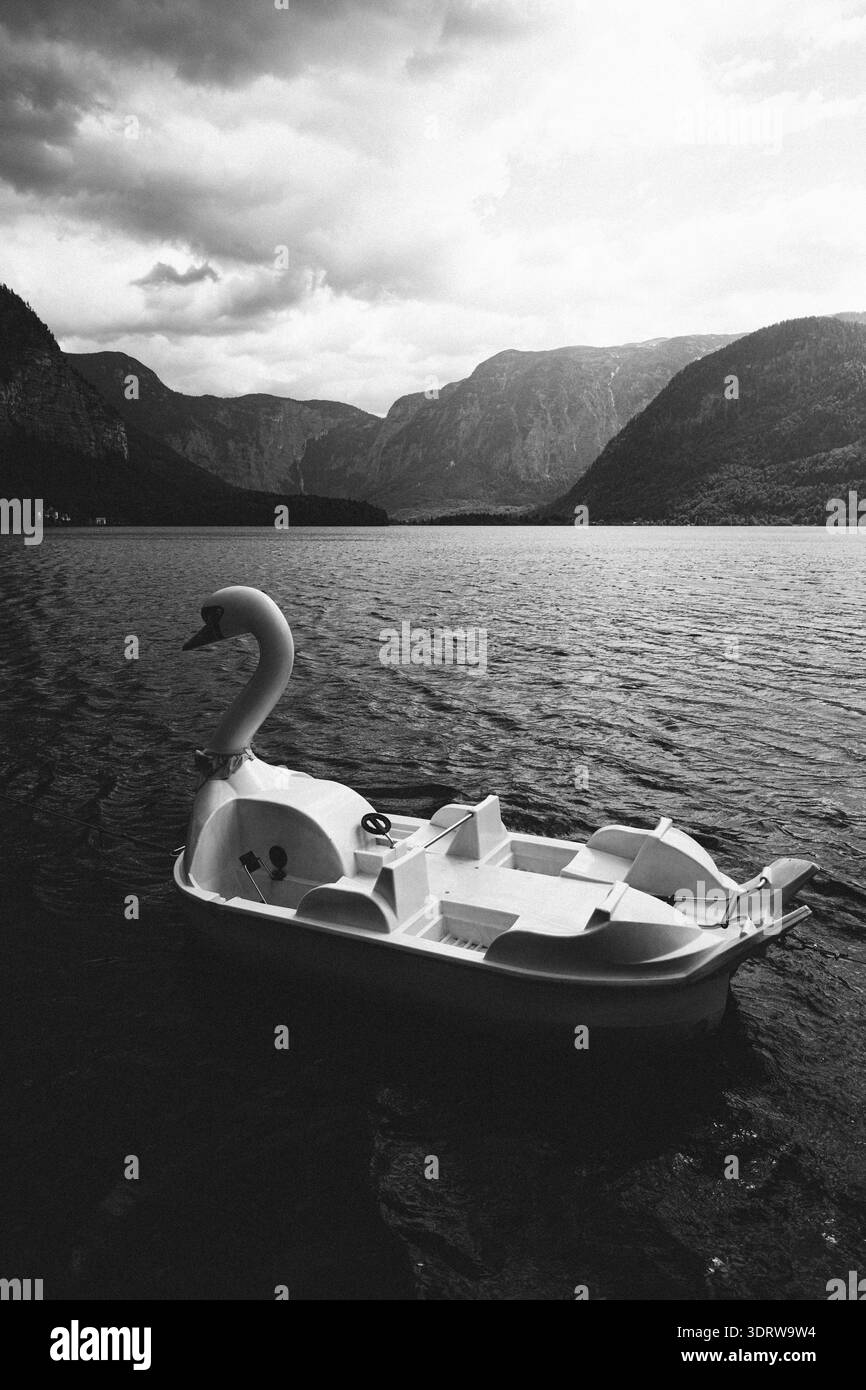 Swan Tretboot schwimmt ruhig auf einem ruhigen See, umgeben von majestätischen Bergen Stockfoto