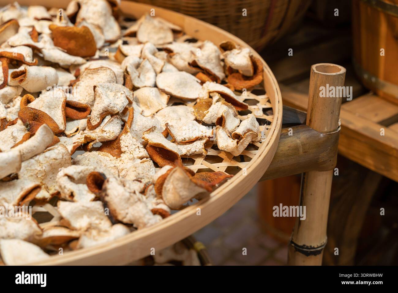 Getrocknete Mandarinen-Orangenschale (Chenpi), die auf einem Bambussieb angeordnet und durch Sonnentrocknen der Schale der Mandarinen hergestellt wird, bis sie aromatisch wird. Stockfoto