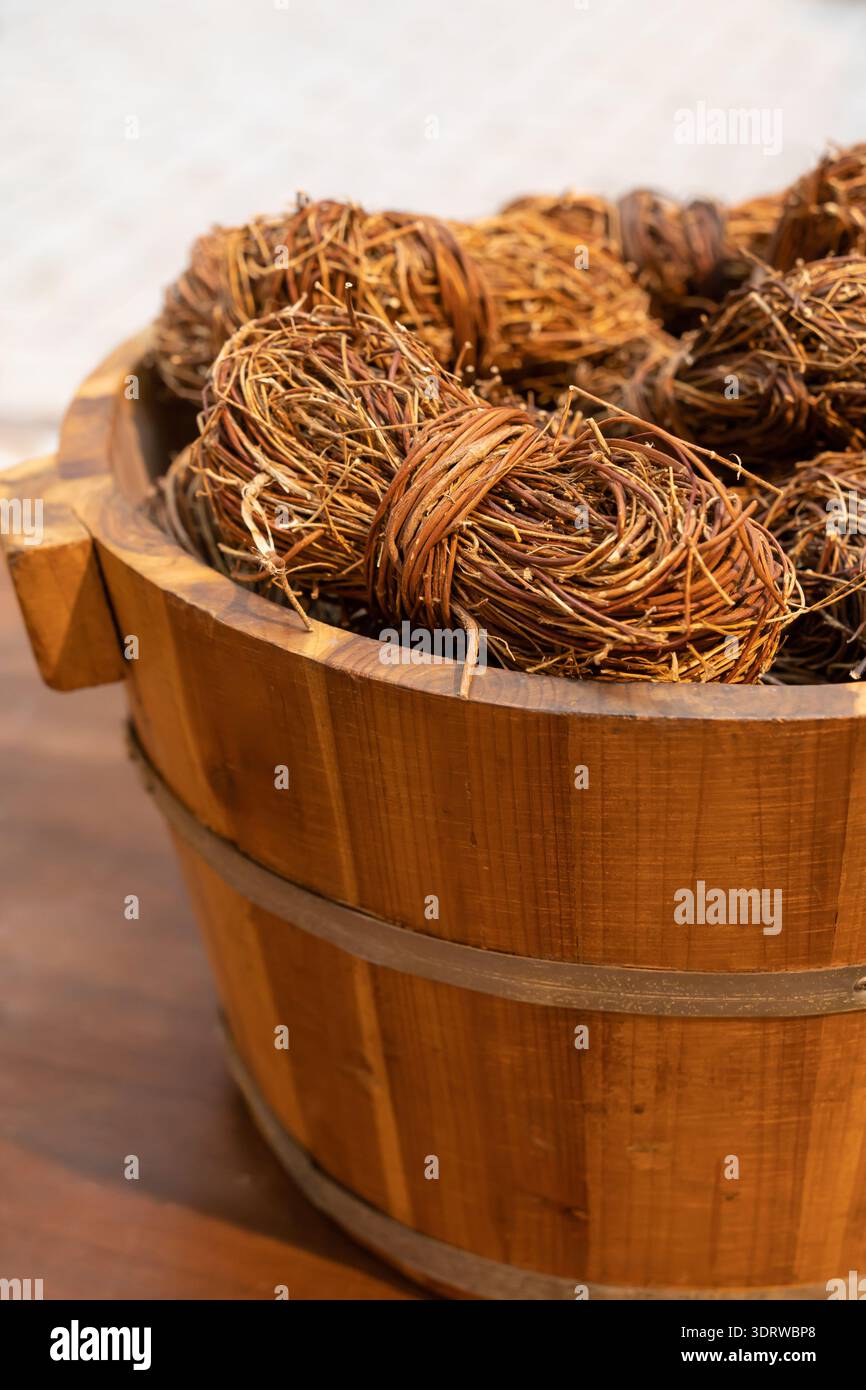 Ein rustikaler Holzeimer voller dekorativer Rattan- und Korbkugeln, der ein natürliches Herzstück im Bauernhausstil ist. Stockfoto