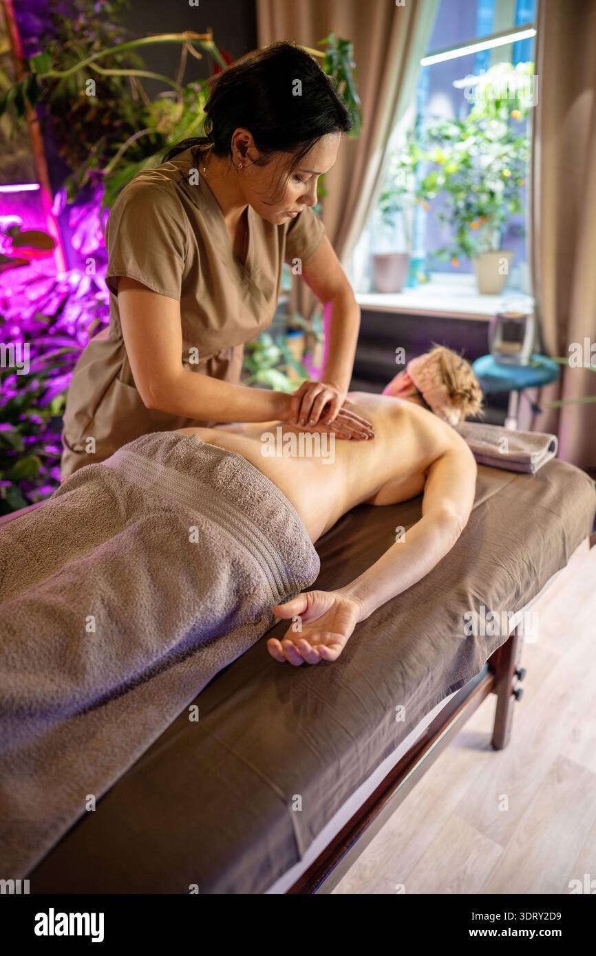 Frau, die sich auf dem Spa-Bett in der Schönheitsklinik, Ganzkörpertherapie für Gesundheit und Wellness entspannt. Stockfoto