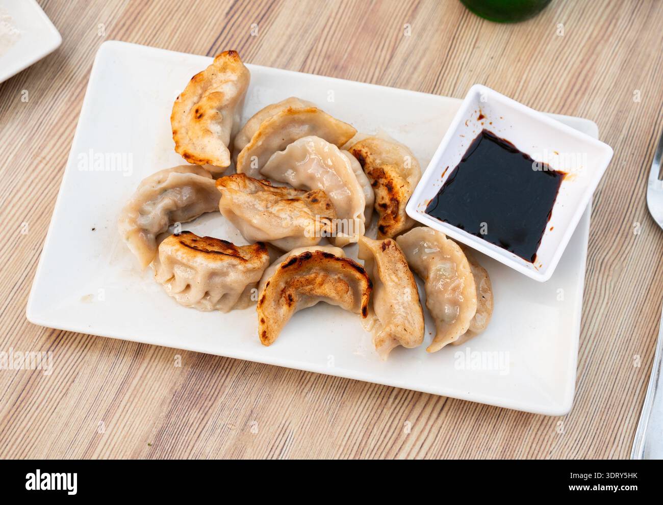 Teller mit gebratenen chinesischen Gyoza-Knödeln und Schüssel mit Sojasauce Stockfoto