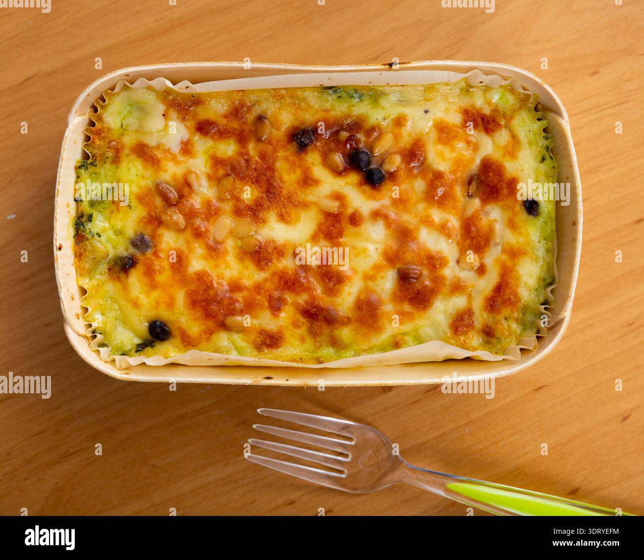 Auf dem Holztisch wird die Lasagne im Ofen unter Käsekruste gebacken Stockfoto