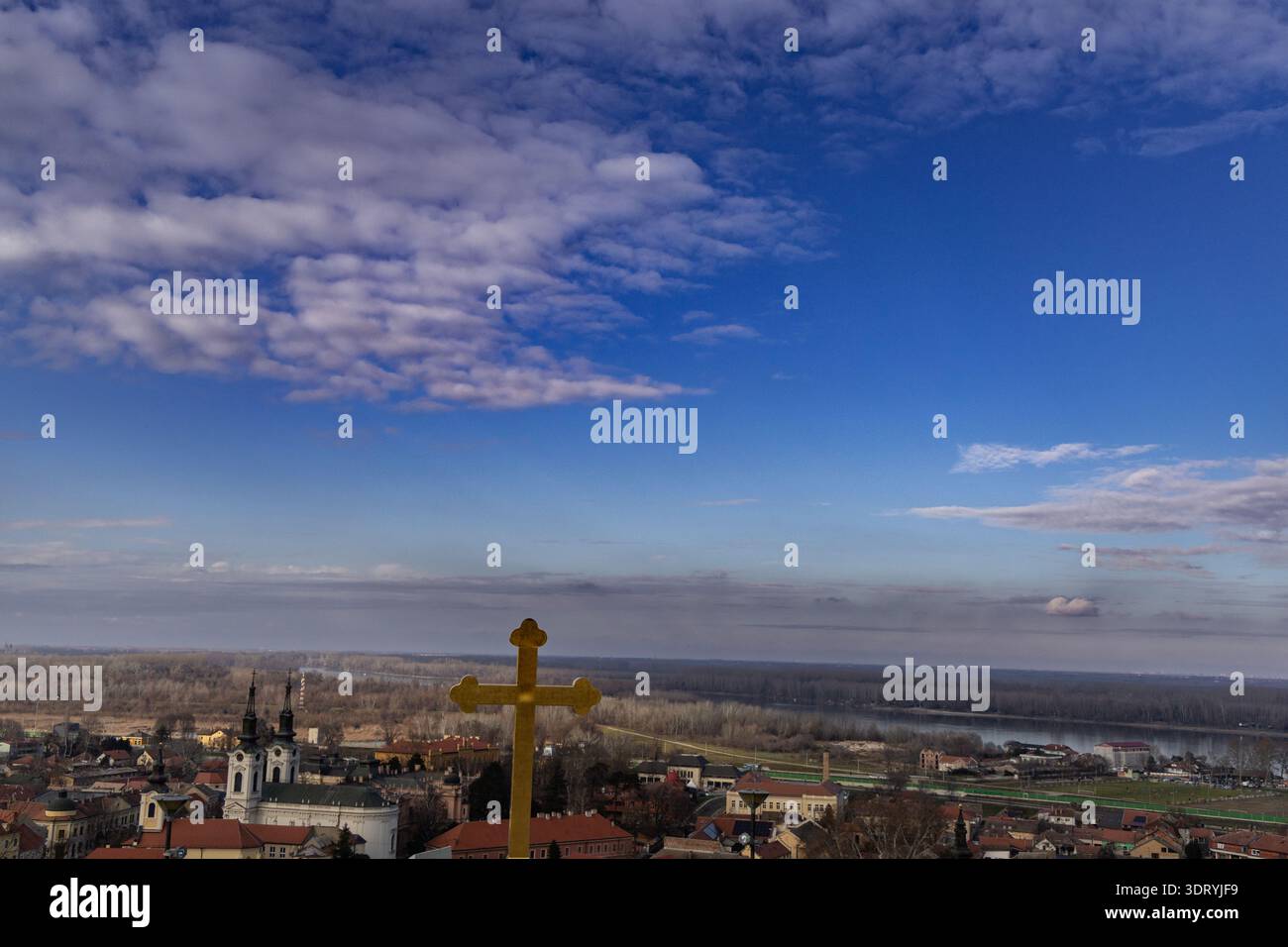Goldenes Kreuz Über Riverside Town Unter Wolken Stockfoto