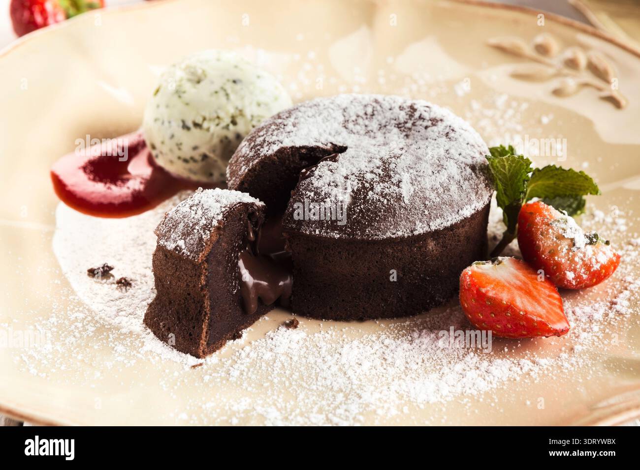 Köstliches Schokoladendessert mit Melting Center serviert mit Eis und Erdbeeren auf einem Teller Stockfoto