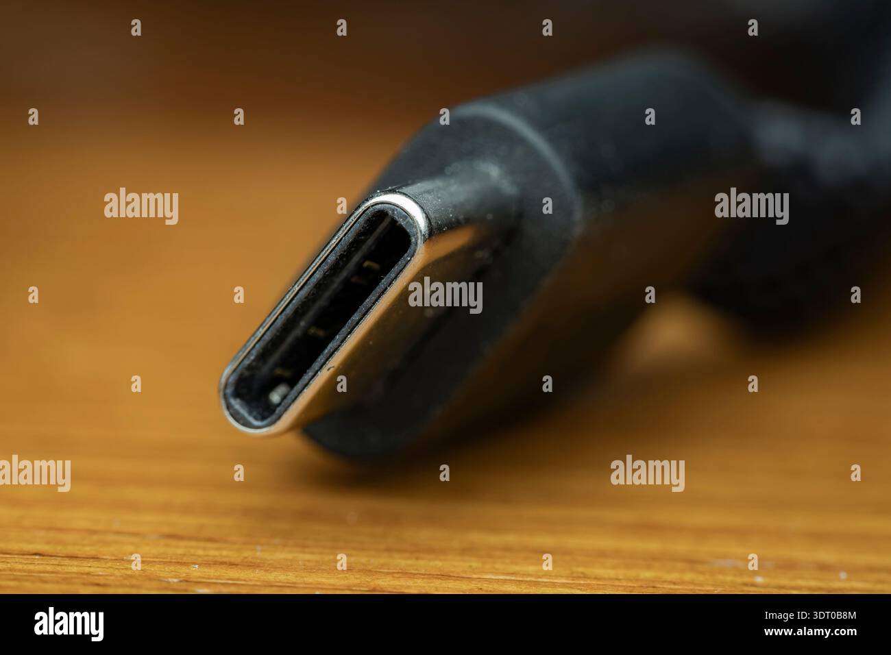 Makroaufnahme eines USB-C-Kabelsteckers auf einer Holzoberfläche, die Technologie und Konnektivität veranschaulicht Stockfoto