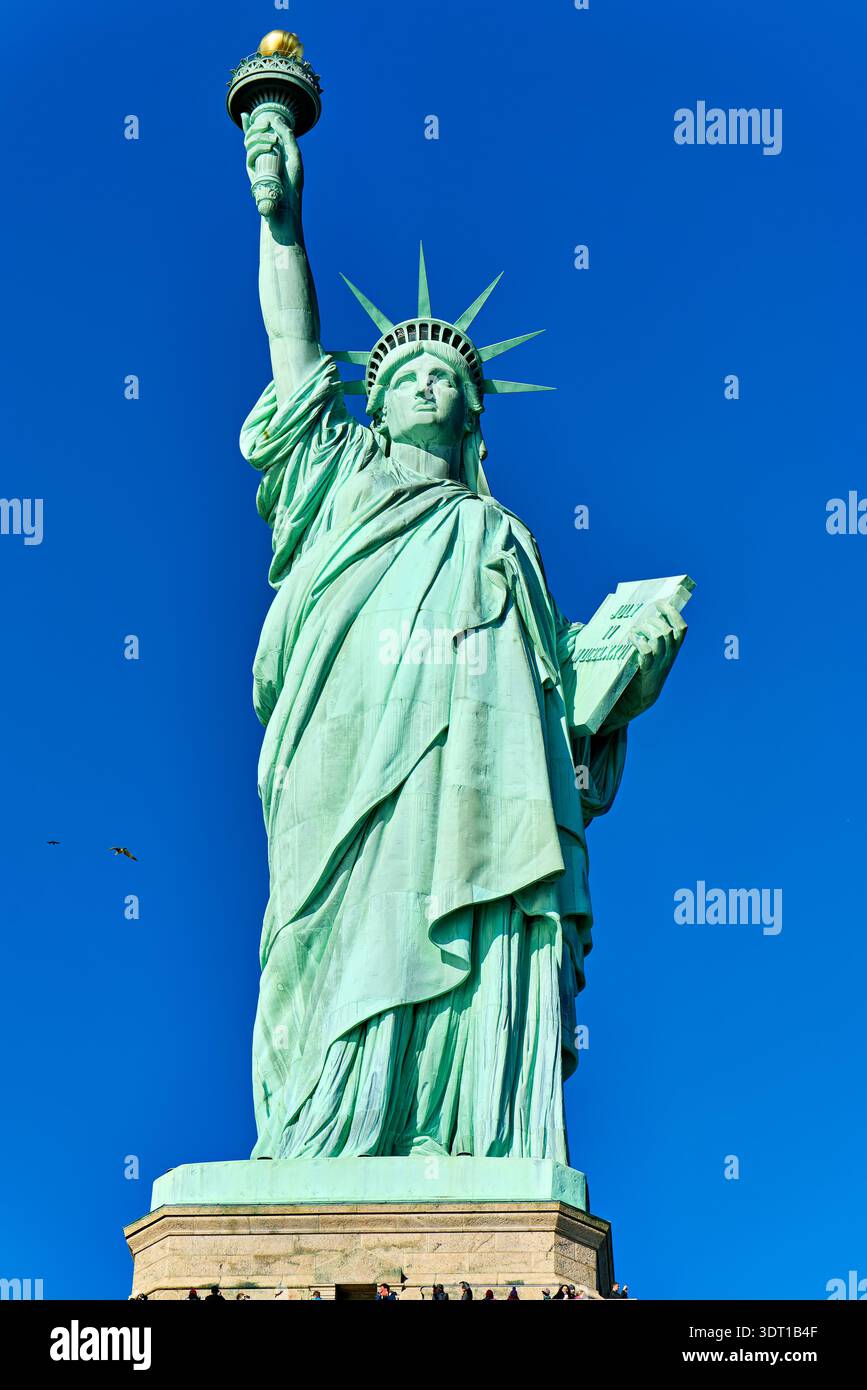 Besucher sehen die Freiheitsstatue in New York. Die Statue steht hoch und hält eine Fackel in einer Hand. Viele Leute genießen die Aussicht. Stockfoto