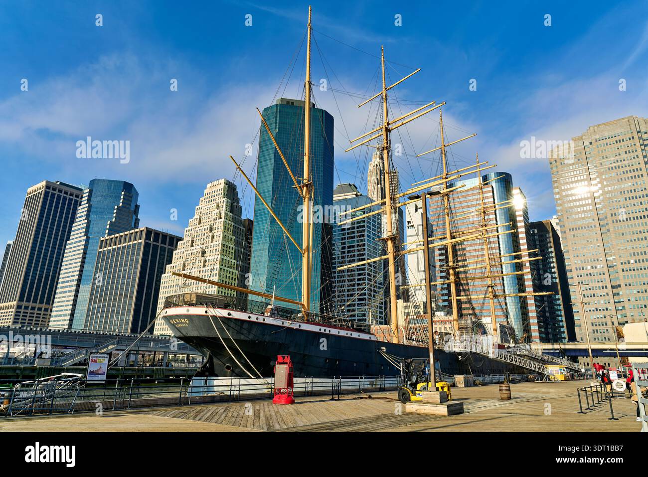 Das Segelboot Peking liegt im Hafen von New York, während sich Wolkenkratzer im Hintergrund unter einem klaren blauen Himmel erheben. Stockfoto