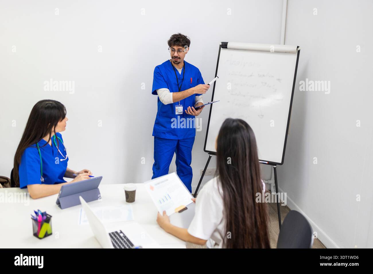 Ein professionelles medizinisches Team versammelt sich zu einem Meeting. Zwei Ärzte in blauem Peeling und eine Krankenschwester in weißer Uniform arbeiten zusammen und diskutieren Strategien für Pati Stockfoto
