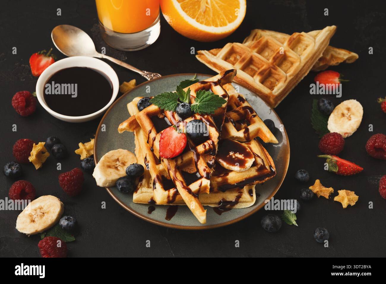 Köstliche Waffelcollage mit Obst und Sirup auf einem dunklen Tisch Stockfoto