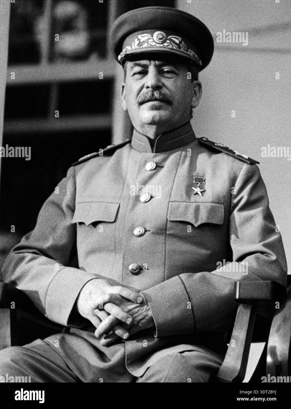 Dieses beeindruckende Schwarzweiß-Foto aus dem Jahr 1943 zeigt Joseph Stalin, den damaligen Premierminister der Sowjetunion, sitzend und direkt in die Kamera blickend. Er trägt Militäruniform, mit Medaillen und einer verzierten Mütze, während einer wichtigen Kriegskonferenz. Stockfoto