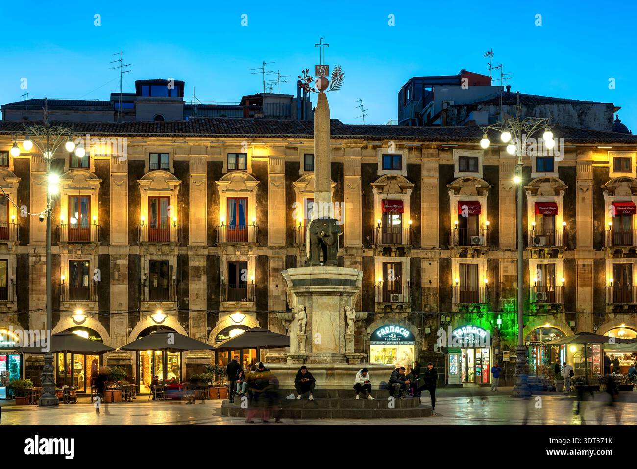 Lephanter Brunnen, beleuchtet zur blauen Stunde, mit Menschen, die sich auf der Piazza Duomo in Catania, Sizilien, Italien versammeln Stockfoto
