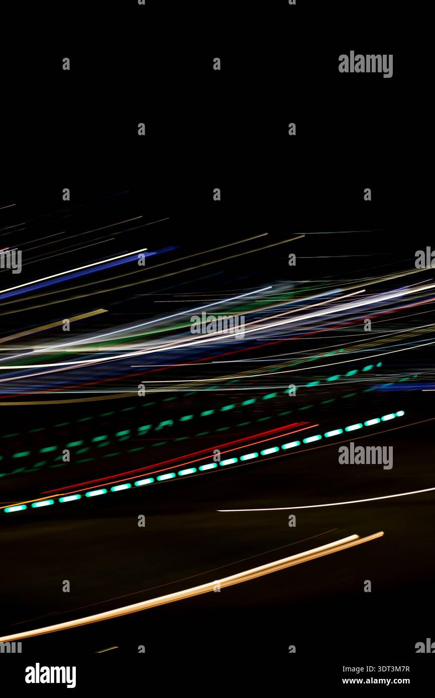 Die diagonalen Lichtstreifen auf Schwarz sorgen für schnellen Verkehr, und das gepunktete Bokeh in Neonlicht deutet auf den Rhythmus und die Distanz des Rücklichts hin Stockfoto