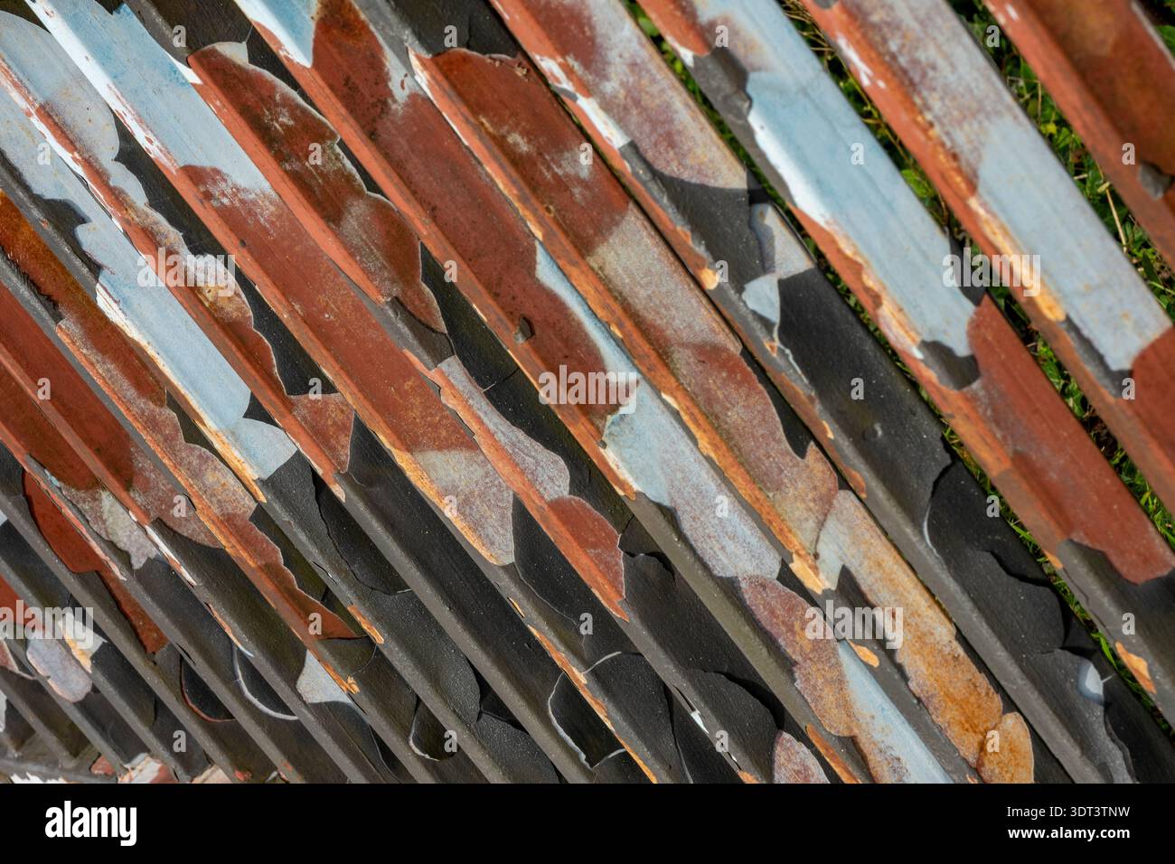 Abstraktes Bild abblätternder Lacke auf Stahlgeländern unter Belichtung früherer Farbschichten und rostiger Oberflächen. Stockfoto