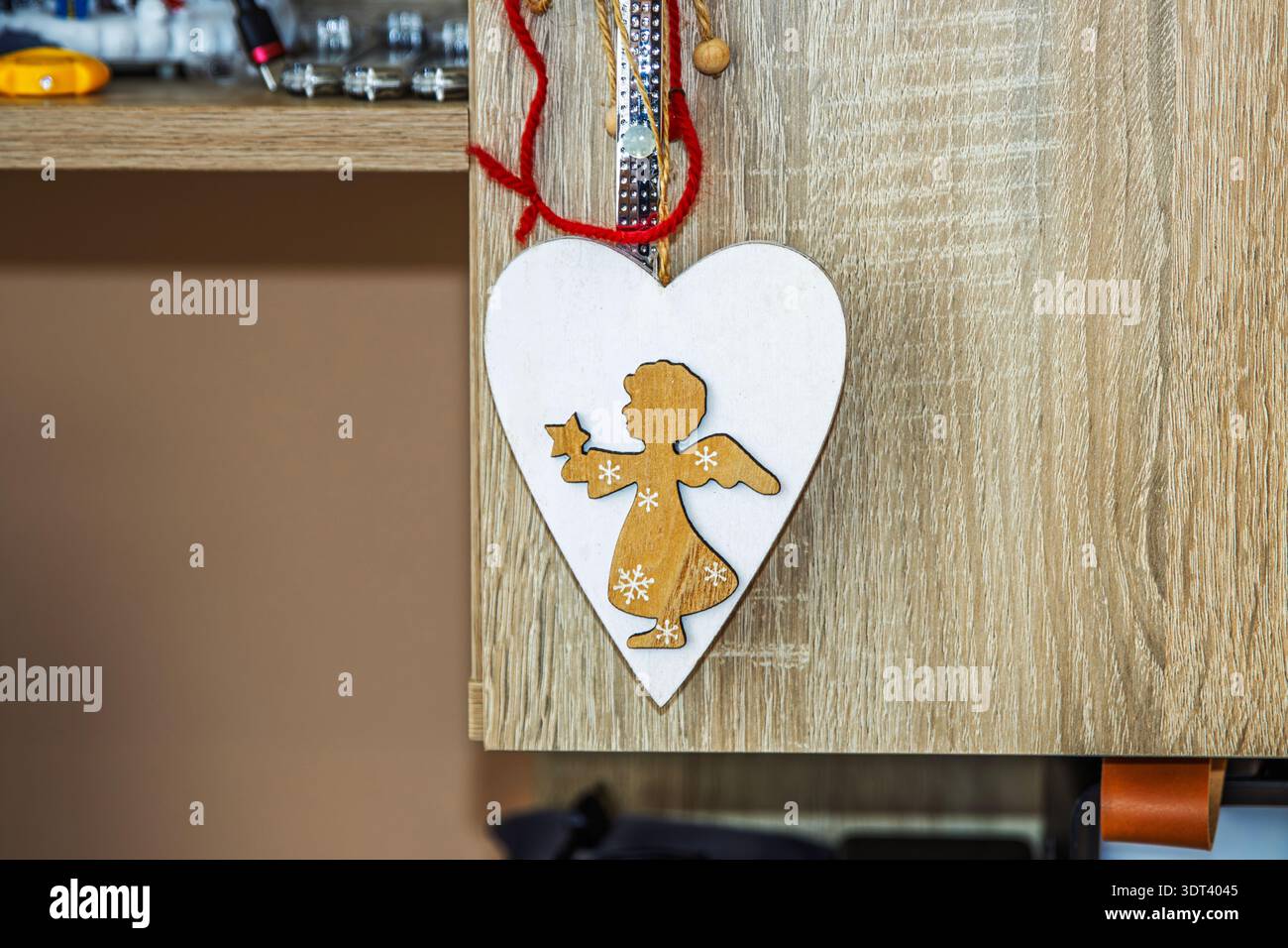 Hölzerner Weihnachtsschmuck in Herzform mit geschnitzter Engelsilhouette auf rustikaler Holzoberfläche Stockfoto