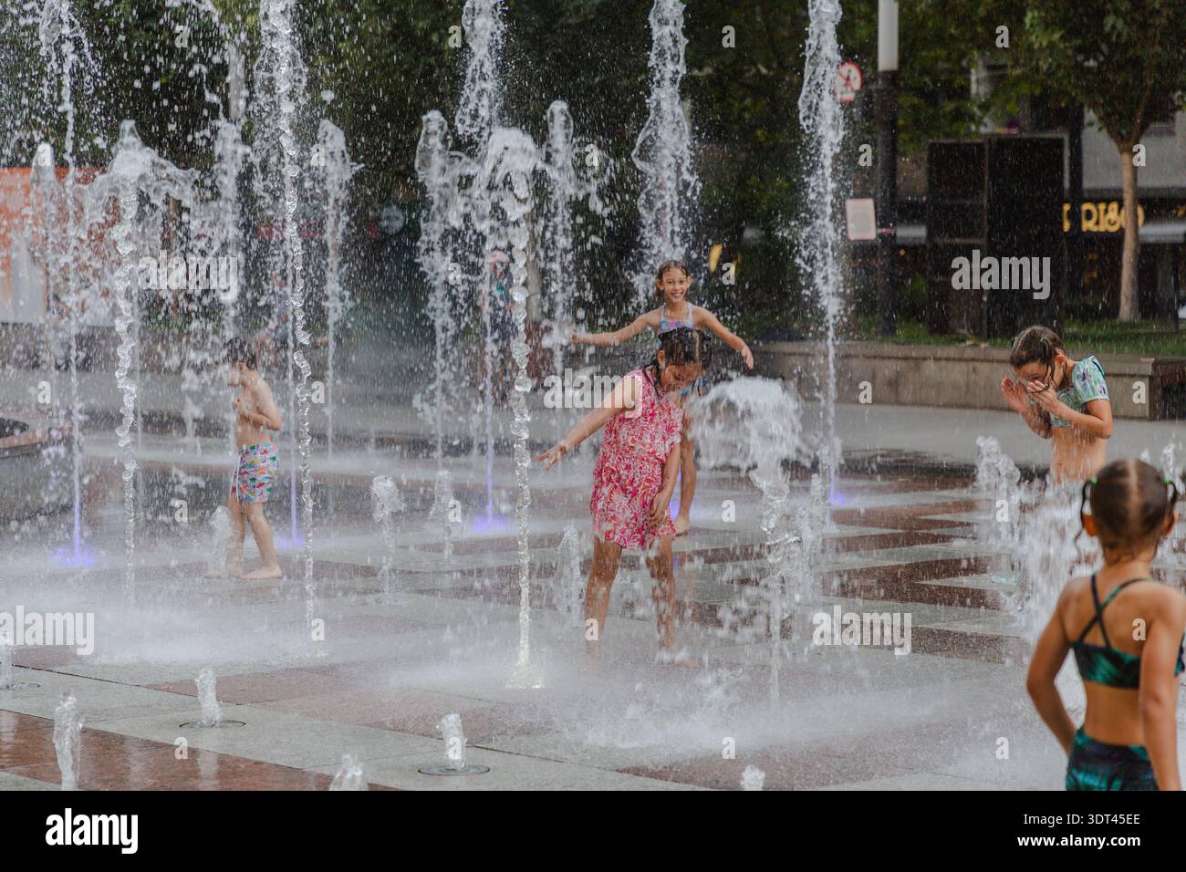Jerewan, Armenien - 26. August 2025: Blick auf Kinder, die in der erfrischenden Kühle eines Stadtbrunnens getaucht sind, und ihr Lachen ertönt im Funkeln Stockfoto