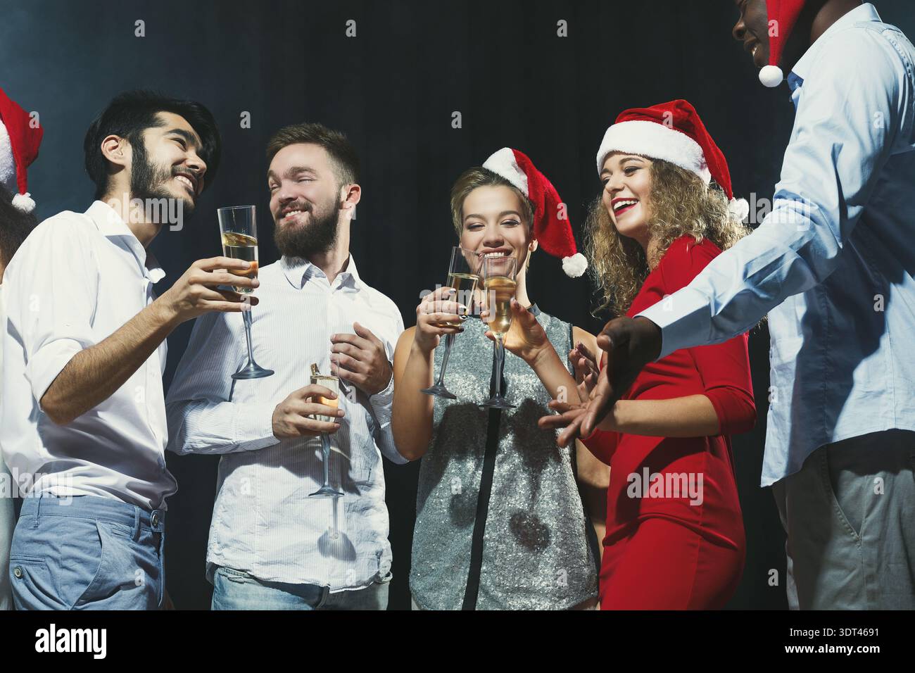 Eine Gruppe von Freunden feiert die Weihnachtszeit mit Getränken und Lächeln Stockfoto