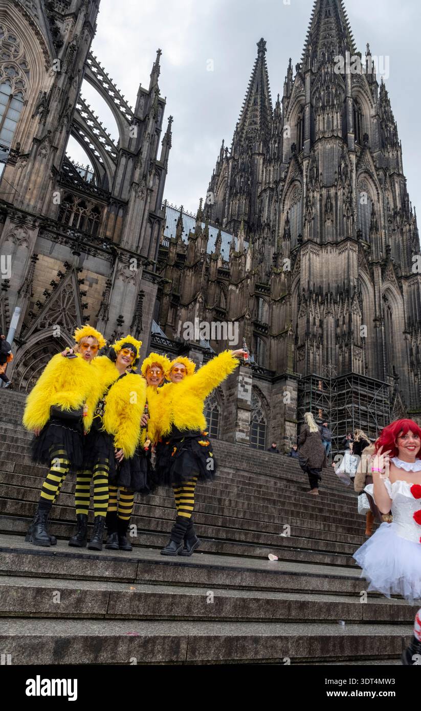 Während des Karnevals posieren Karnevalsfreunde in knallgelben Kostümen auf den Stufen des Kölner Doms Stockfoto