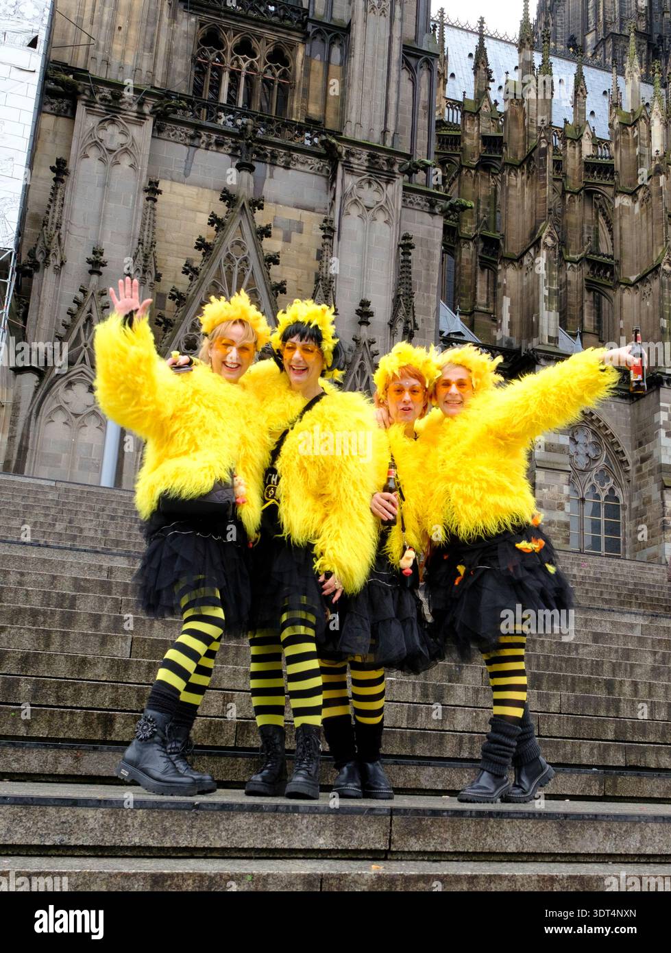 Während des Karnevals posieren Karnevalsfreunde in knallgelben Kostümen auf den Stufen des Kölner Doms Stockfoto
