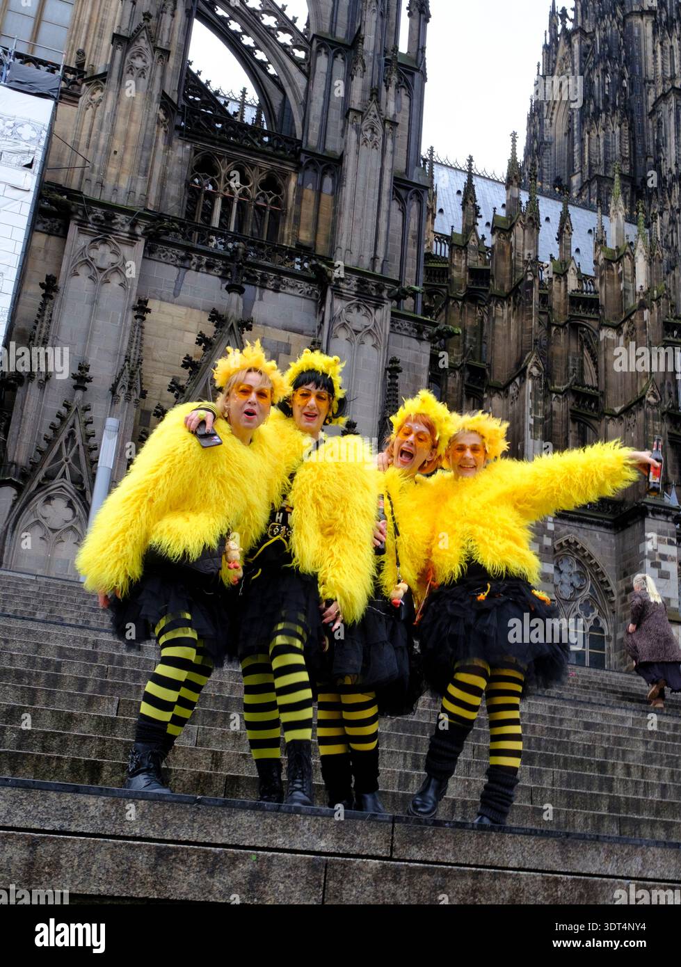 Während des Karnevals posieren Karnevalsfreunde in knallgelben Kostümen auf den Stufen des Kölner Doms Stockfoto