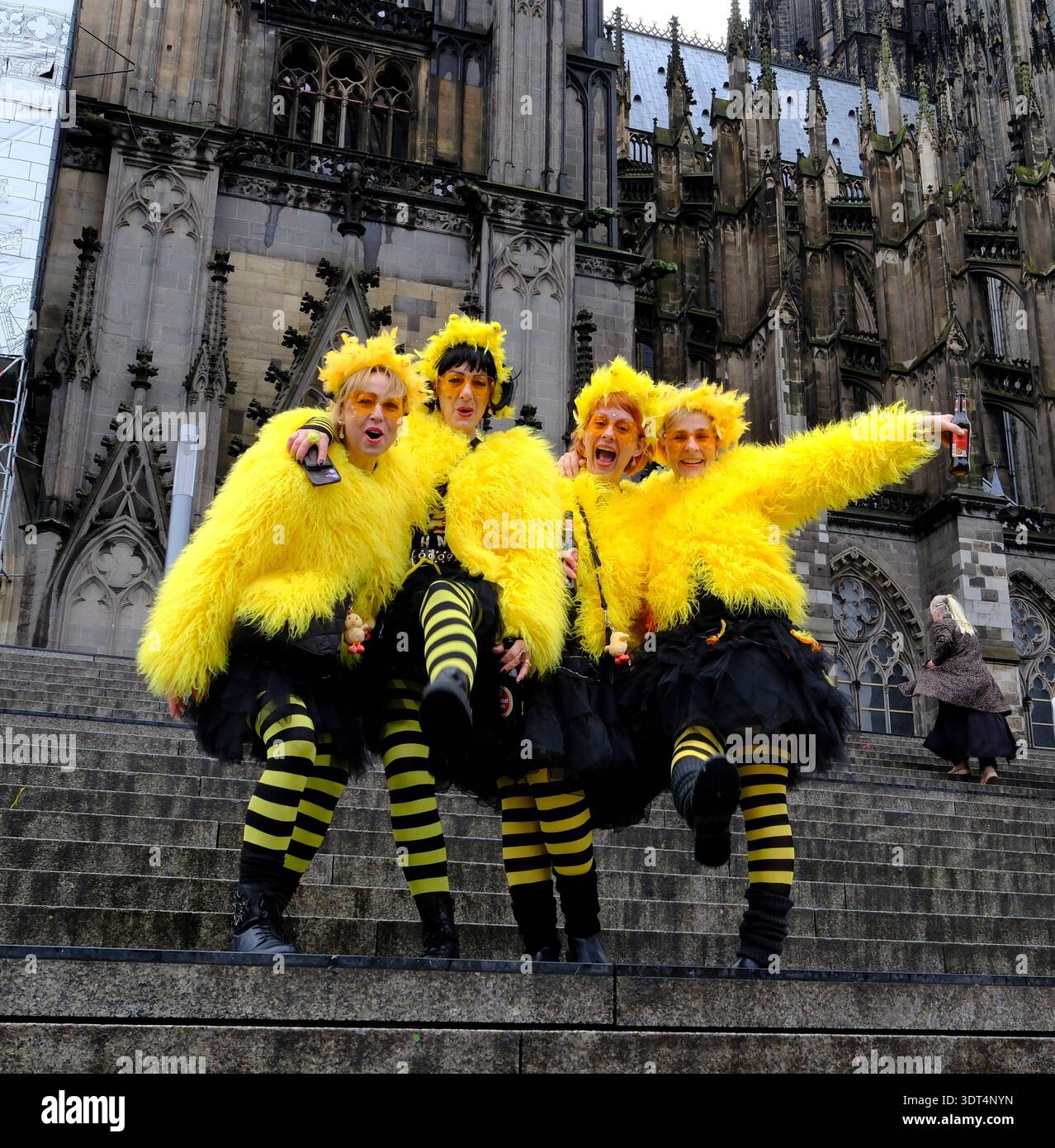 Während des Karnevals posieren Karnevalsfreunde in knallgelben Kostümen auf den Stufen des Kölner Doms Stockfoto