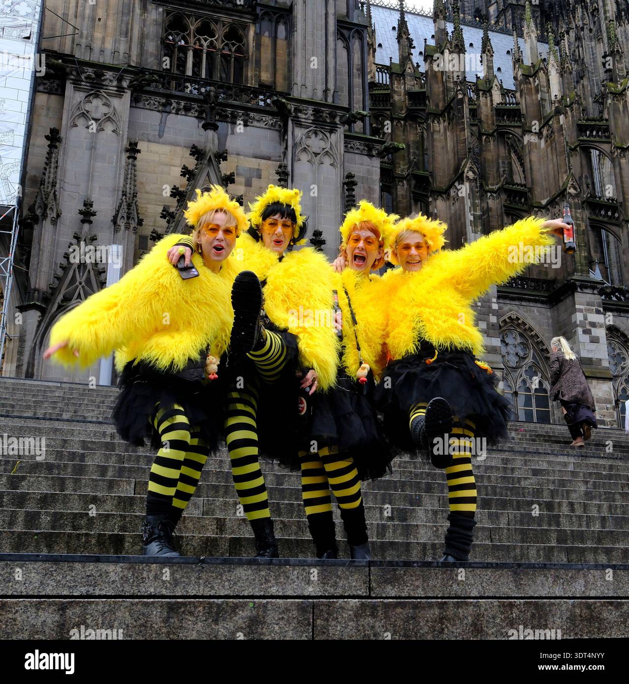 Während des Karnevals posieren Karnevalsfreunde in knallgelben Kostümen auf den Stufen des Kölner Doms Stockfoto