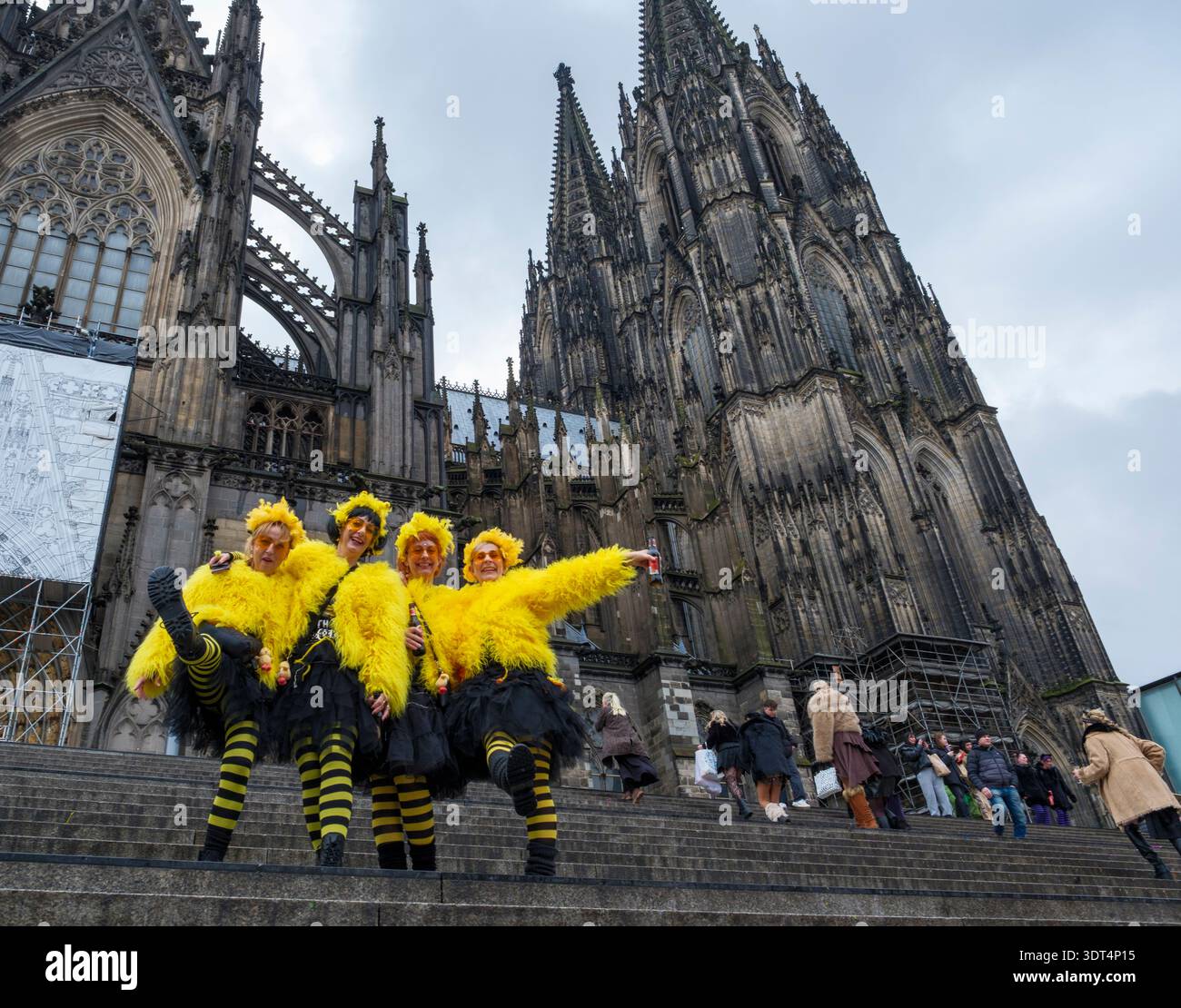 Während des Karnevals posieren Karnevalsfreunde in knallgelben Kostümen auf den Stufen des Kölner Doms Stockfoto