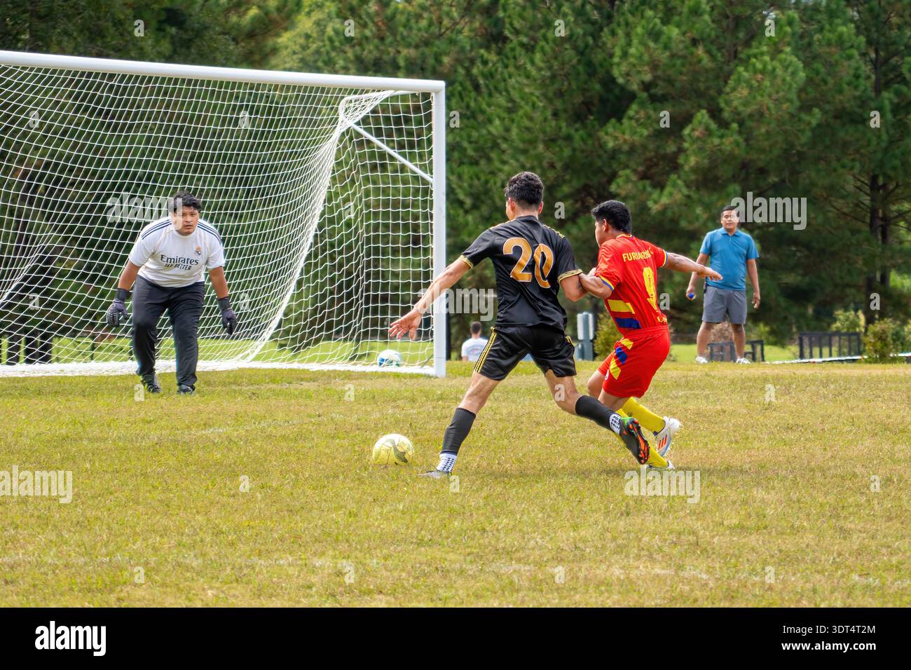 Ein Spieler springt während eines Community Amateur-Fußballspiels in Knightdale auf das Tor zu. In öffentlichen Parks finden regelmäßig informelle und Fußballspiele statt. Stockfoto