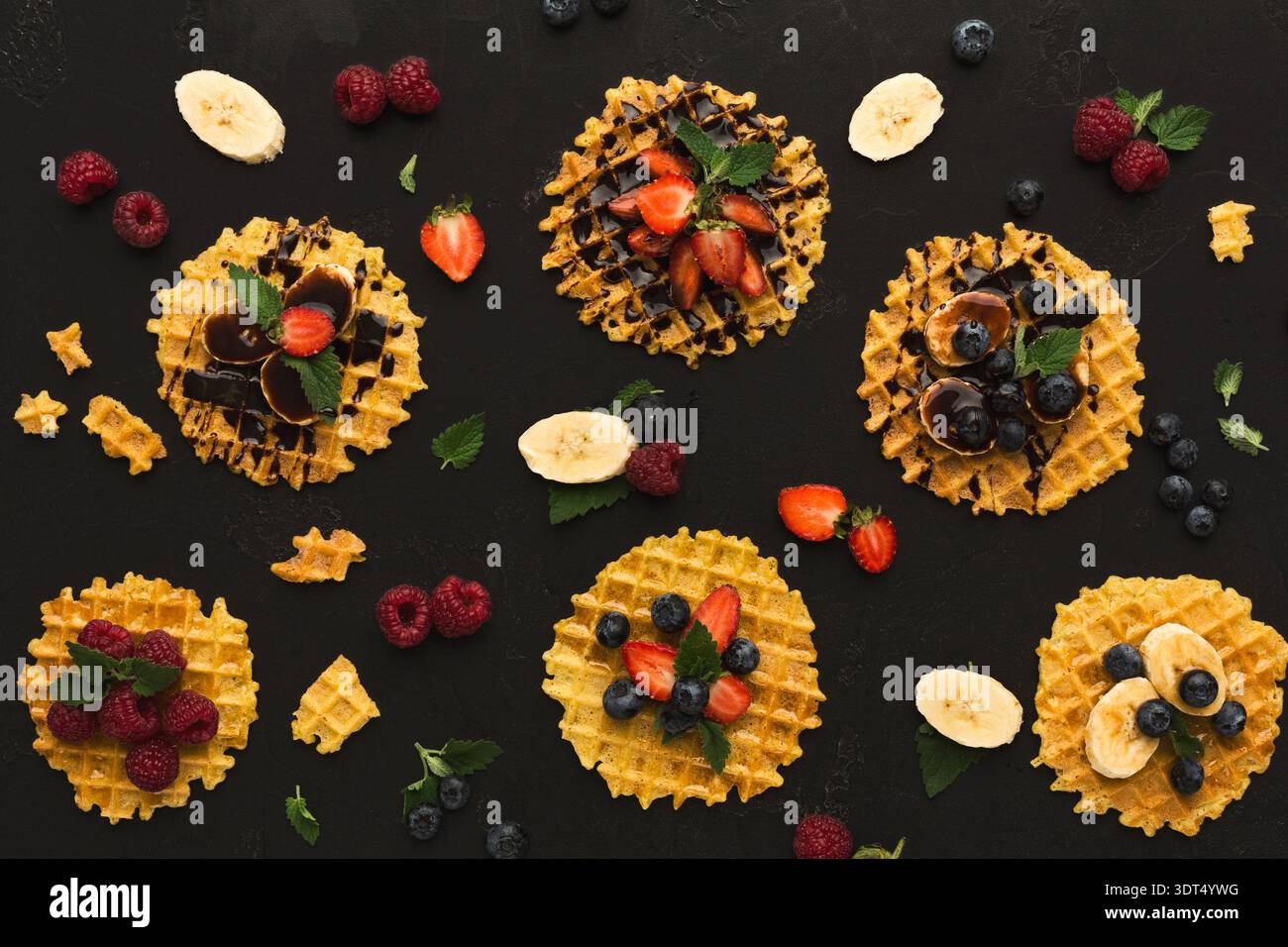 Verschiedene Arten von Waffeldesserts auf kreative Weise auf dunkler Oberfläche angeordnet Stockfoto