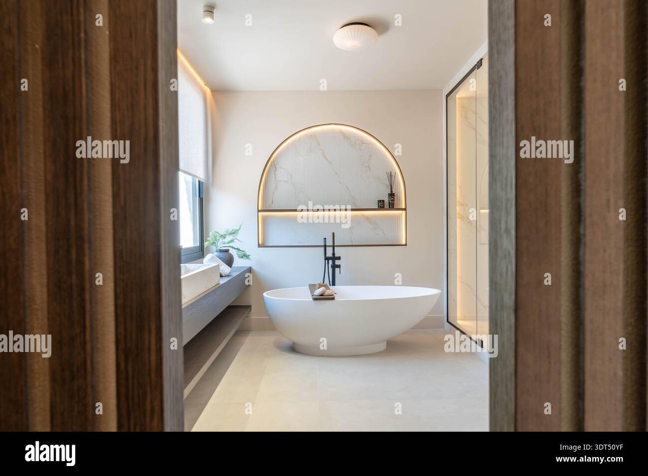 ein Bild eines luxuriösen beleuchteten Badezimmers mit freistehender Badewanne in einem mediterranen Ferienhaus Stockfoto