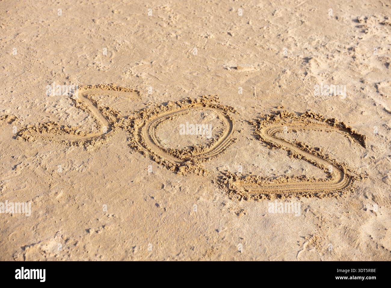 SOS-Nachricht geschrieben auf Sandy Beach Surface Emergency Help Concept Hintergrund Stockfoto