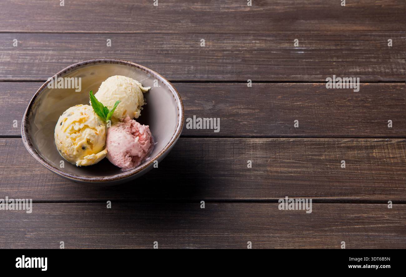 Verschiedene Eissorten serviert in einer Schüssel auf einem Holztisch in einem Café Stockfoto