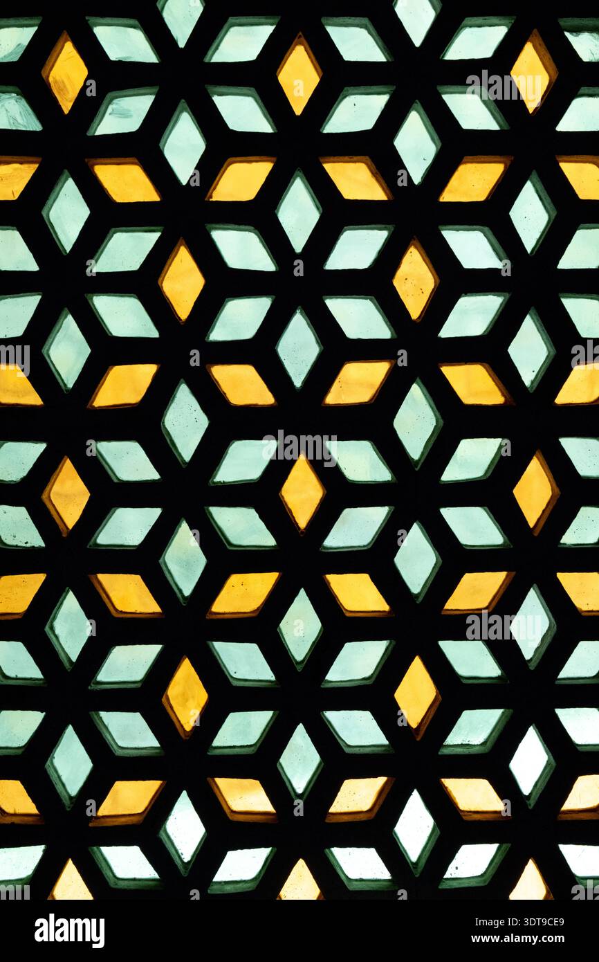 Geometrisches Gittermuster mit gelbem und grünem Glas, das sich wiederholende Diamantformen bildet, dekorative architektonische Bildschirme. Stockfoto