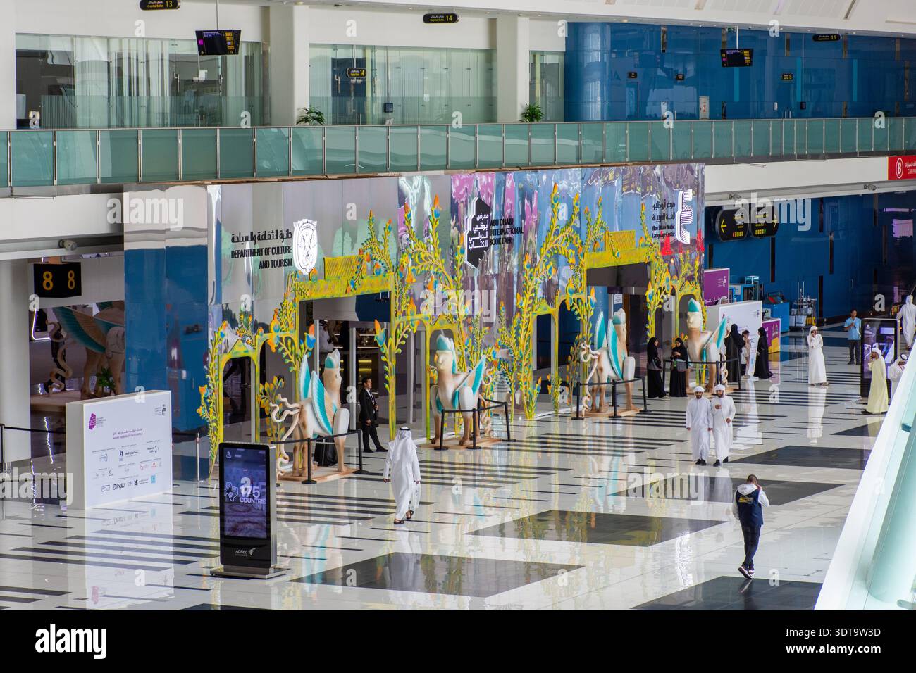 Besucher, die in der Nähe des farbenfrohen Eingangs der internationalen Buchmesse Abu Dhabi im National Exhibition Centre, VAE, spazieren gehen. Stockfoto