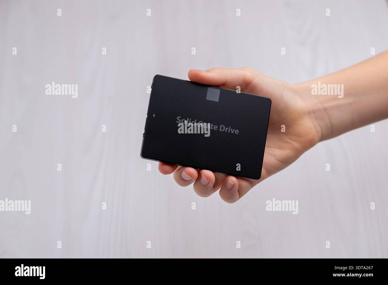 Handgehaltenes SATA-Solid-State-Laufwerk vor neutralem Hintergrund, modernes Computerspeichergerät für schnelle Datenübertragung und Aktualisierung Stockfoto