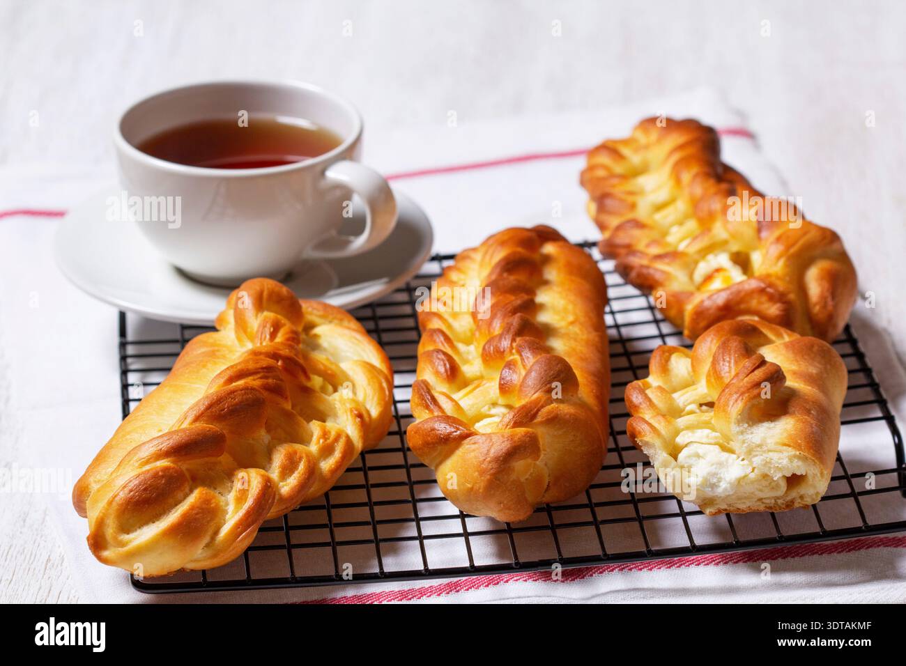 Geflochtene Brötchen mit Hüttenkäse-Füllung, serviert mit Tee. Stockfoto