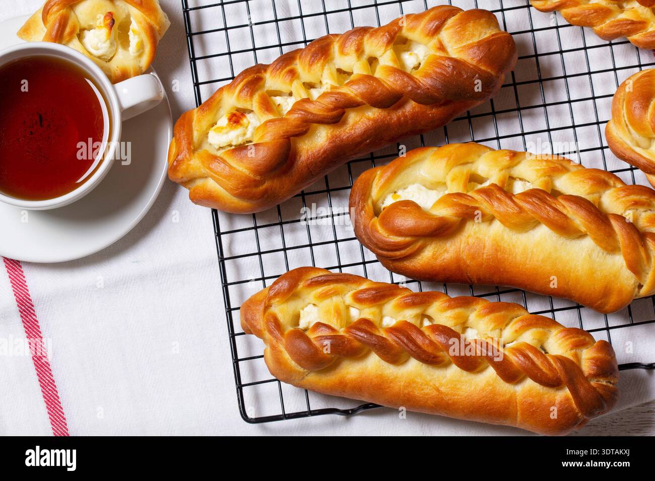 Geflochtene Brötchen mit Hüttenkäse-Füllung, serviert mit Tee. Stockfoto